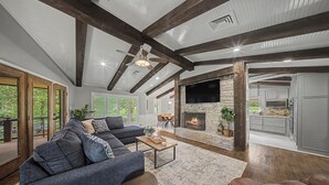Ein geräumiges Wohnzimmer mit Kamin, einer Couch, einem Couchtisch und einem Fernseher.