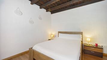 Un dormitorio con cama de madera, mesitas de noche con lámparas e iluminación en la pared.