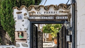 A rustic entrance with a stone archway, a sign reading 'EL PARRAL ALO MIENTO RURAL,' and a mailbox. - Hostal Posada El Parral – Private Pool and Restaurant in the Sierra de Cádiz (Benaocaz)