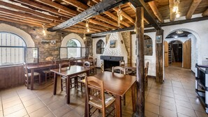 A rustic interior with exposed wooden beams, stone walls, and a fireplace. Tables and chairs are arranged for dining. - Hostal Posada El Parral – Private Pool and Restaurant in the Sierra de Cádiz (Benaocaz)