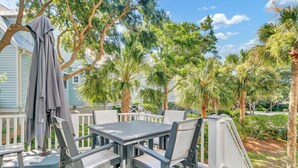 Eine Terrasse im Freien mit Tisch und Stühlen, umgeben von Bäumen und einem Haus.