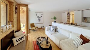 Uma sala de estar moderna com um sofá, uma poltrona, uma mesa de centro e uma lareira.
