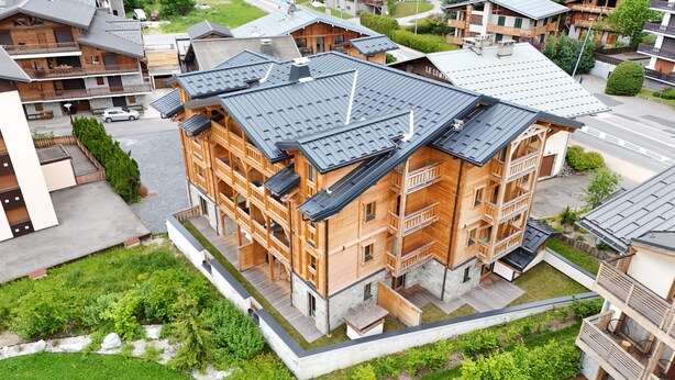 Um edifício de vários andares com varandas, base de pedra e telhado de metal.
