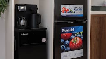 A compact kitchen area with a black refrigerator, a coffee machine, and a small cabinet with a microwave.