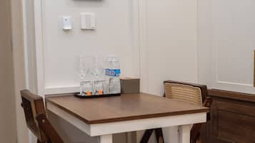 Un comedor con una mesa blanca, sillas de madera oscura y una botella de agua.
