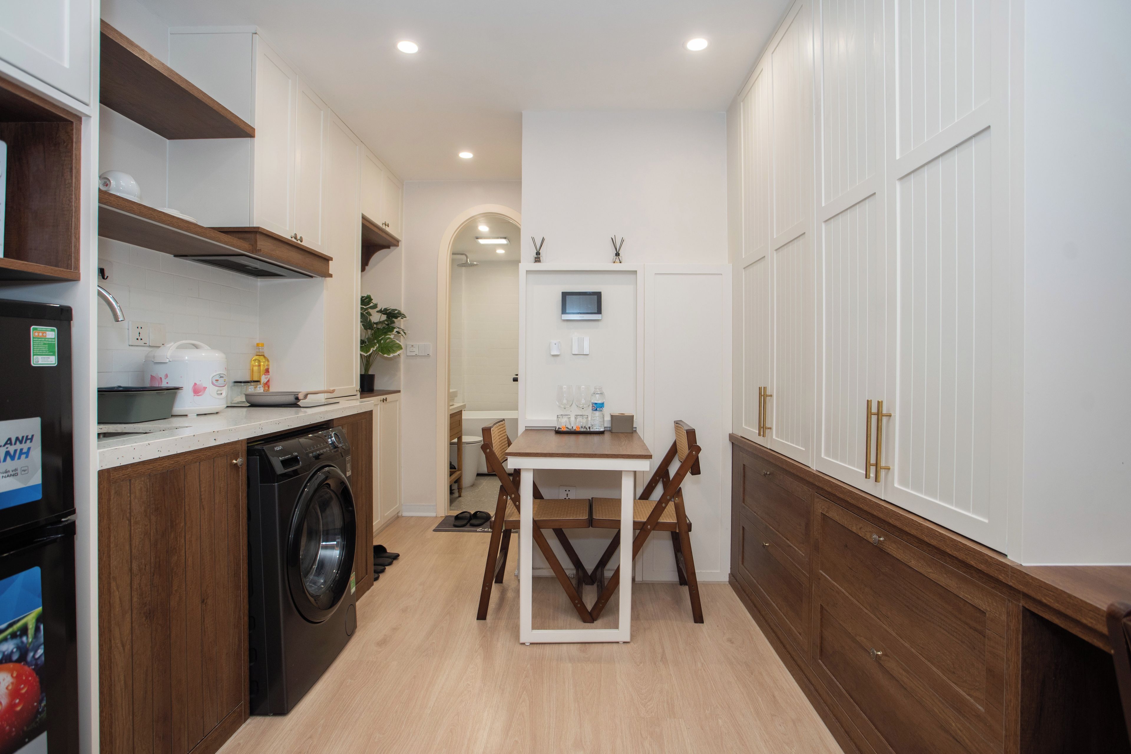 A compact kitchen with a washing machine, a dining table, and a TV.