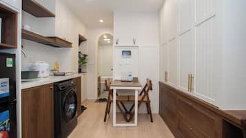 Cocina compacta con lavadora, una mesa de comedor y televisor.