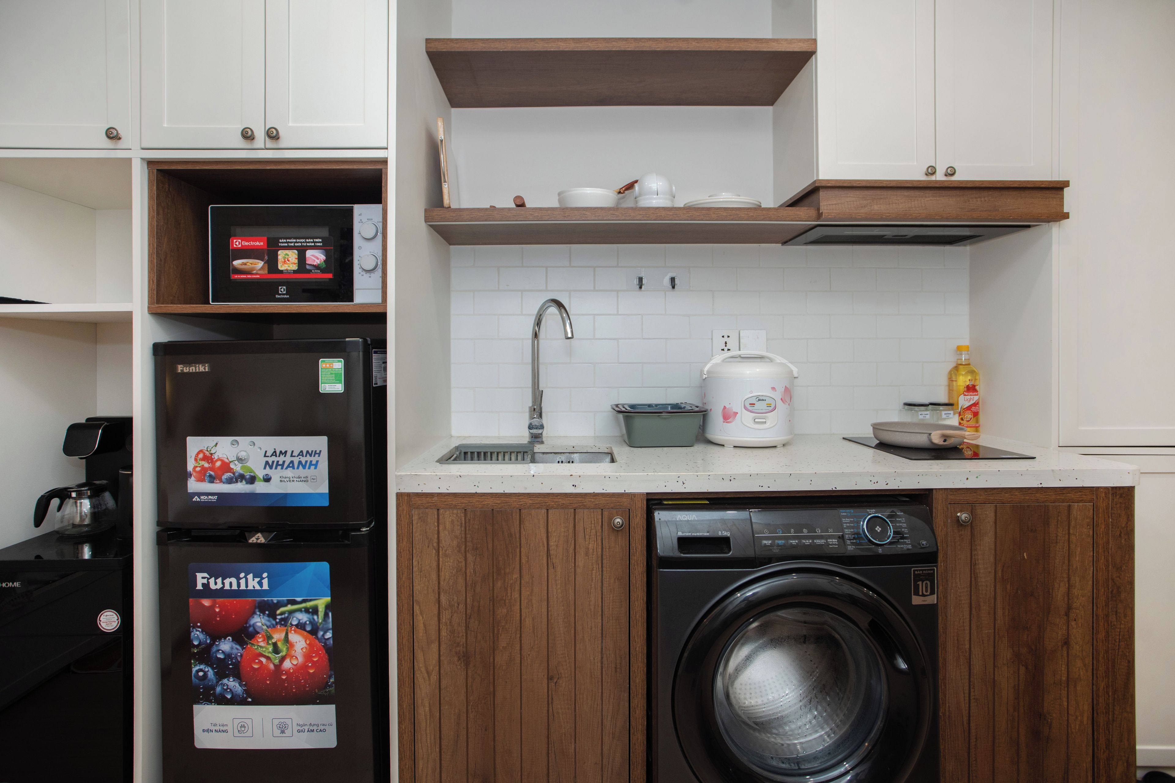 A compact kitchen with a built-in washing machine, a coffee machine, and a microwave.