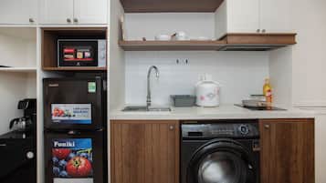 Una cocina compacta con lavadora integrada, cafetera y microondas.