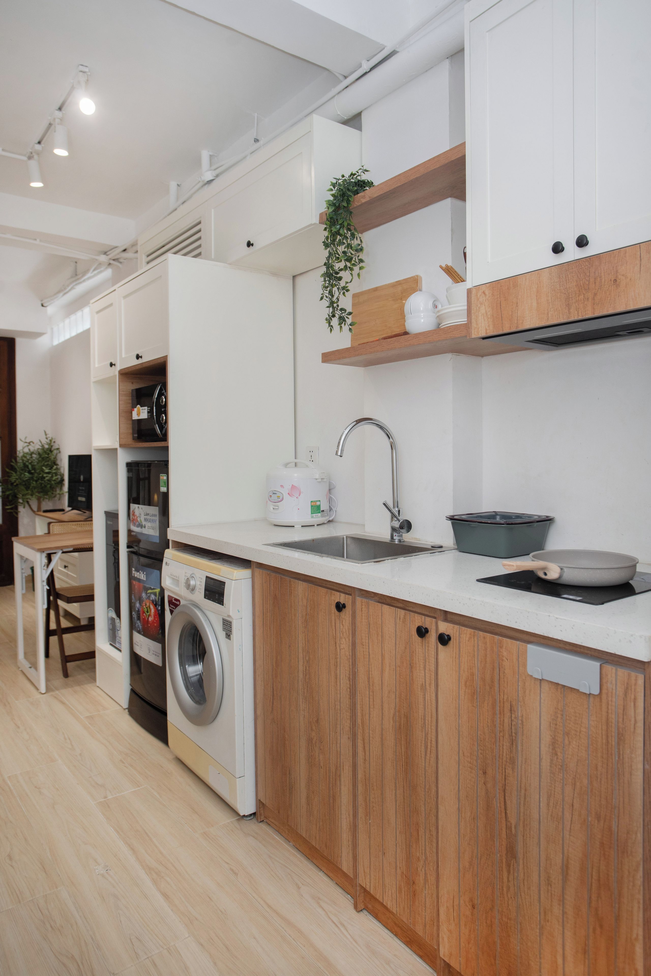 Une cuisine moderne équipée d’un lave-linge intégré, d’un évier et de meubles de rangement en bois.