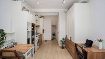Una cocina moderna con armarios de madera, una zona de comedor con mesa y sillas, y un ordenador portátil a la derecha.