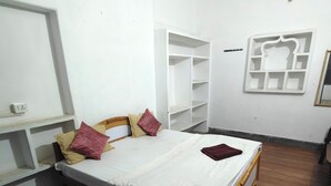 A bedroom with a wooden bed, white walls, and a built-in wardrobe.