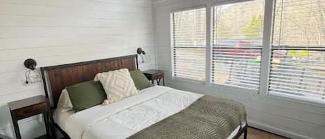 A bedroom with a bed, a ceiling fan, a window, and a view of the outside.