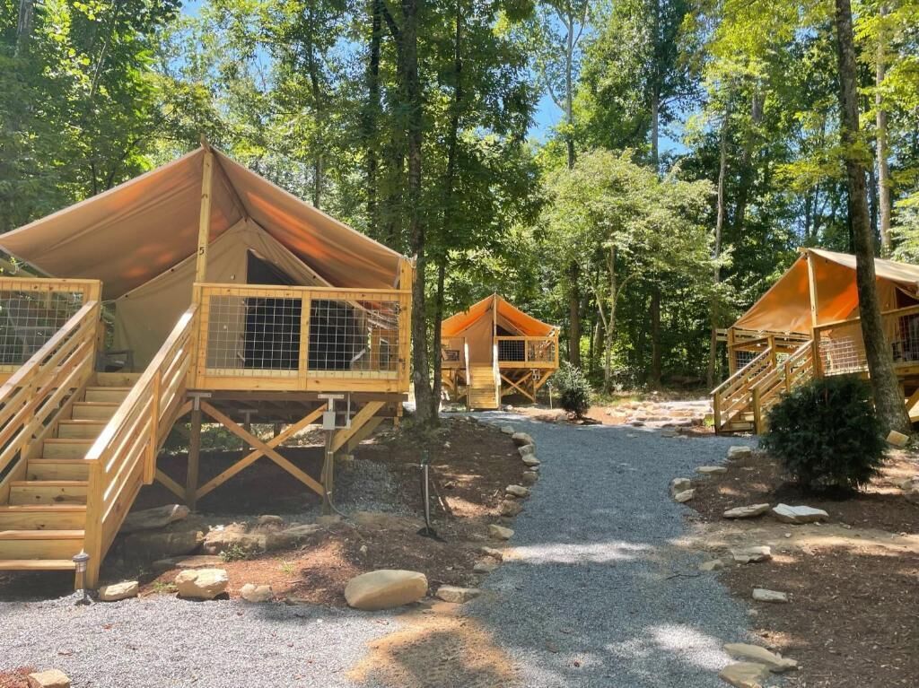 Un camping con cabañas de madera, cada una con una escalera y una entrada cercada.