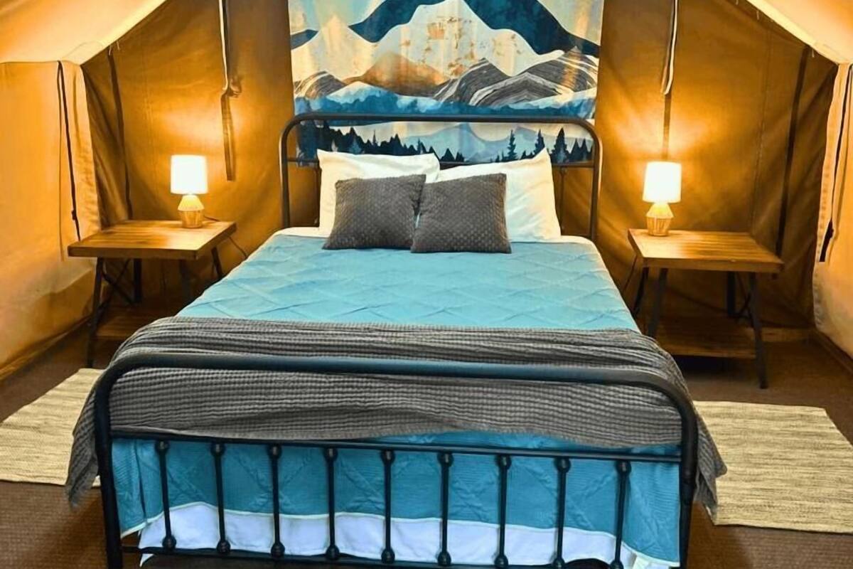 Una habitación con tienda, una cama, dos mesitas de noche y un tapiz grande en la pared.