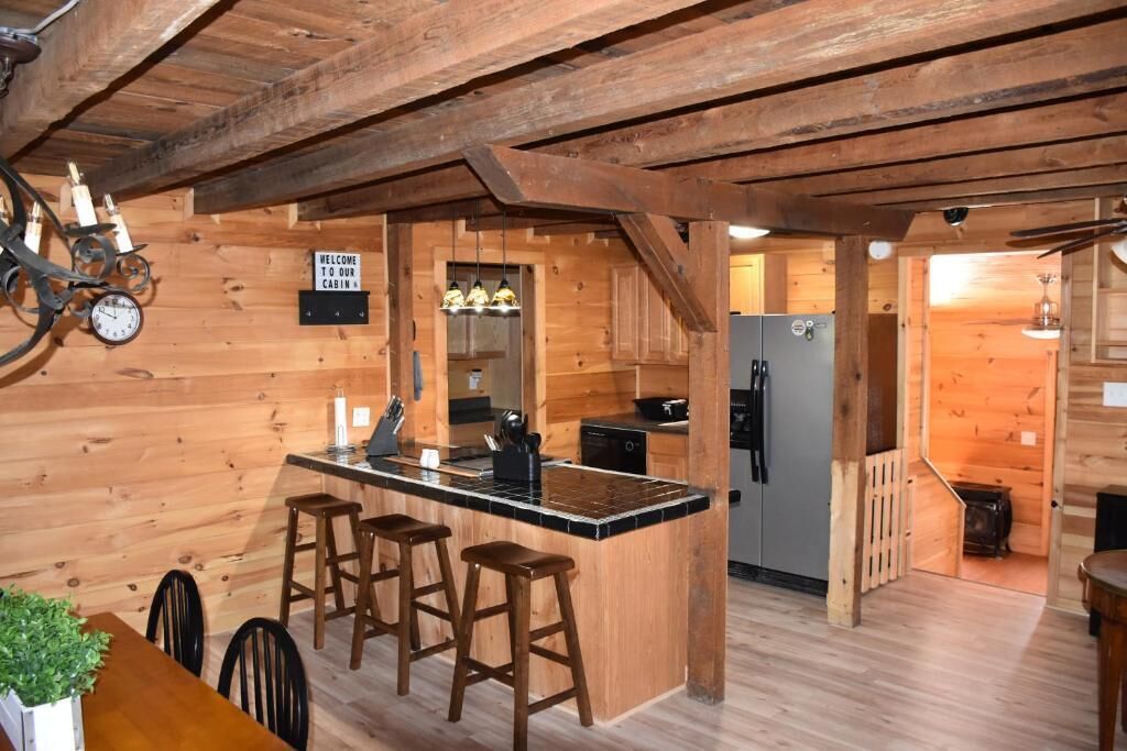 Een houten chalet van binnen met een keuken, een bar en een eettafel met stoelen.