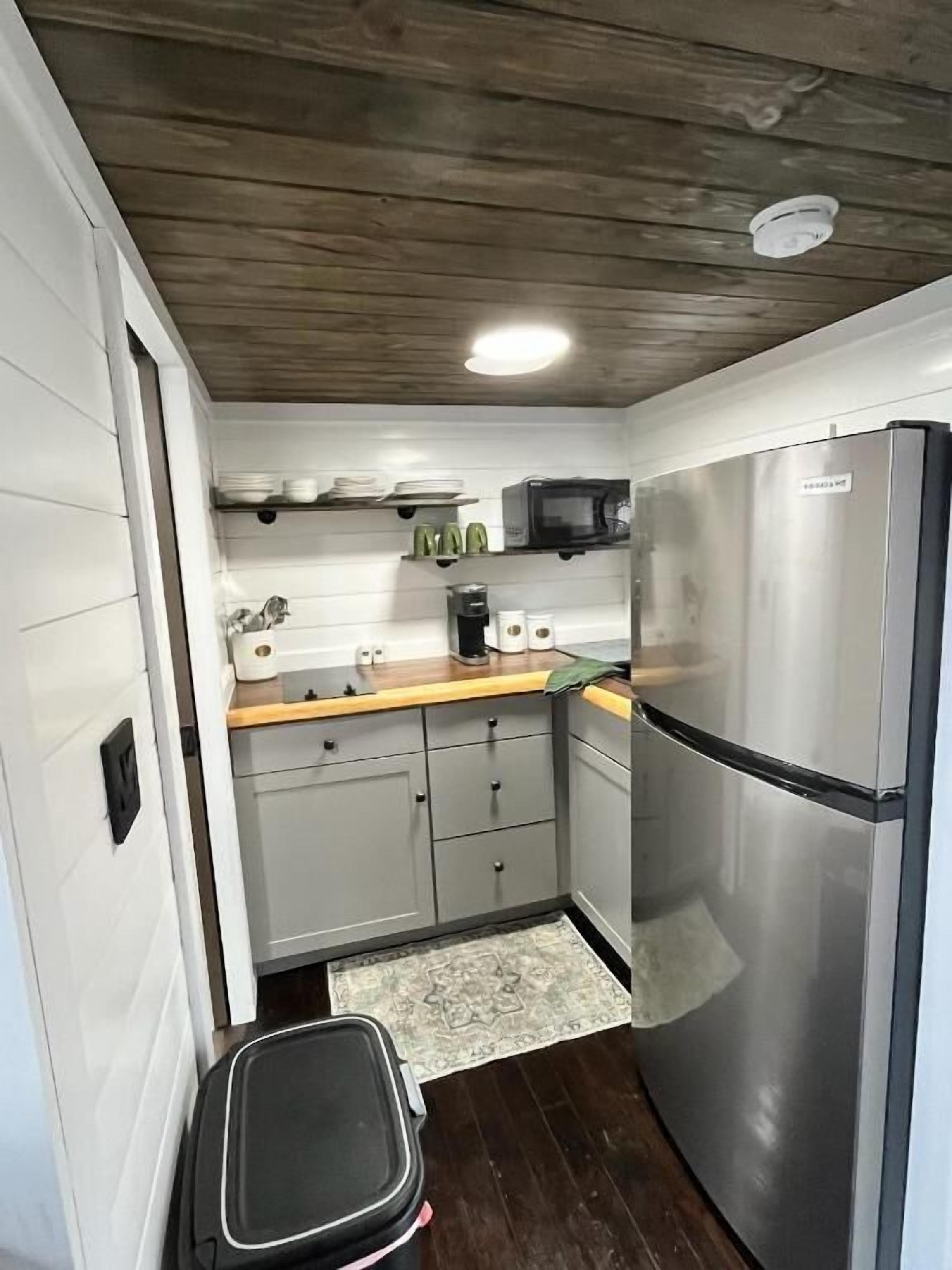 A compact kitchen with a stainless steel refrigerator, a microwave, and a coffee maker on the countertop.