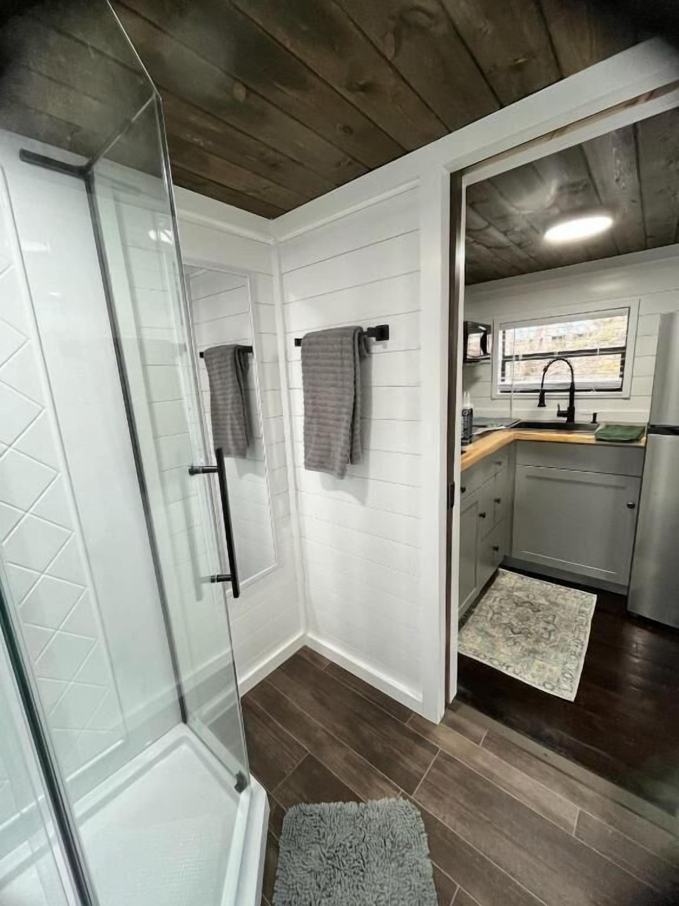 Een badkamer met een douchecabine van glas, een handdoekhouder en een wastafelgedeelte met een raam.
