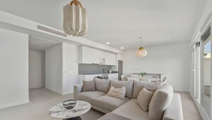 Ein modernes Wohnzimmer mit einer Couch, einem runden Couchtisch und einer Küche im Hintergrund.