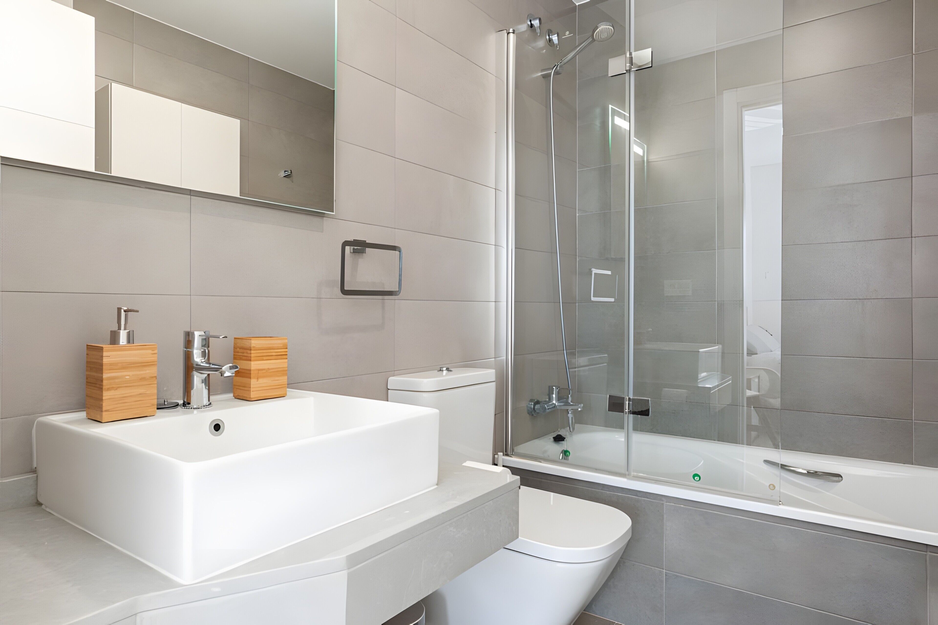 A modern bathroom with a large white sink, a glass-enclosed shower, and a toilet.