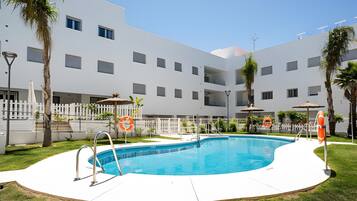 Ein modernes Gebäude mit Swimmingpool, Palmen und Rettungsbojen.