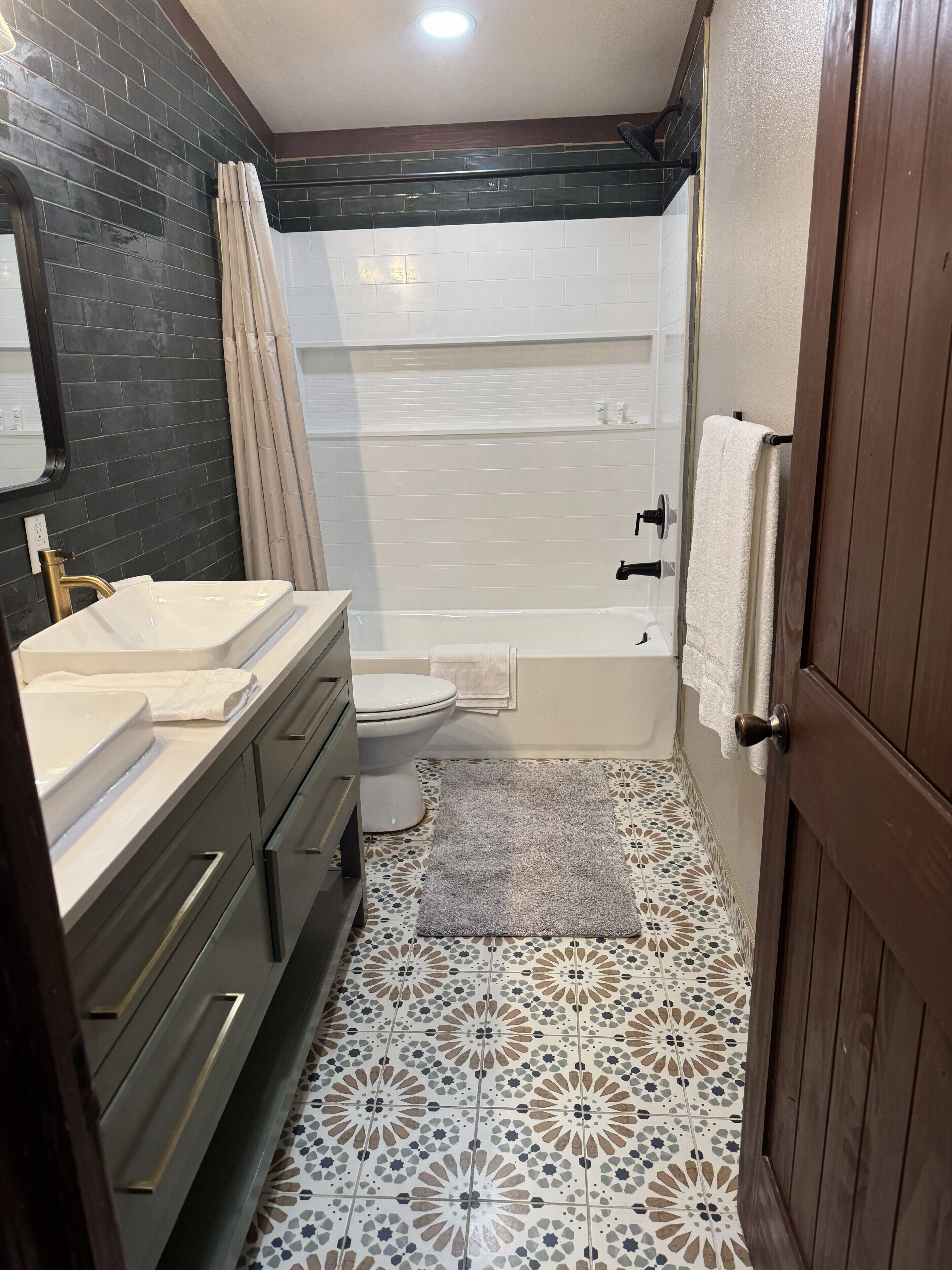 A bathroom with a double sink, toilet, bathtub, and a shower curtain.