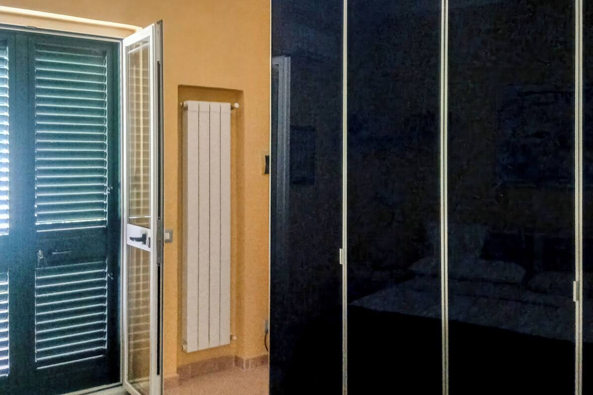 A room with a sliding door, a white door, and a dark sliding closet.