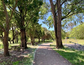 A park with a paved path, picnic tables, and a swing set. - Vila Rola | Heating • Parking • EV Charger • Bikes (Mira)