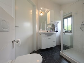A bathroom with a toilet, sink, mirror, and shower area. - Restyled Koningshoeve 6 People (Schoorl)