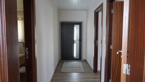 Ein Flur mit Holztüren, eine dunkle Tür am Ende und ein heller Teppich auf dem Boden.