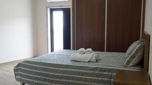 Ein Schlafzimmer mit einem Bett, einem Holzschrank, einem weißen Teppich und einer Klimaanlage.