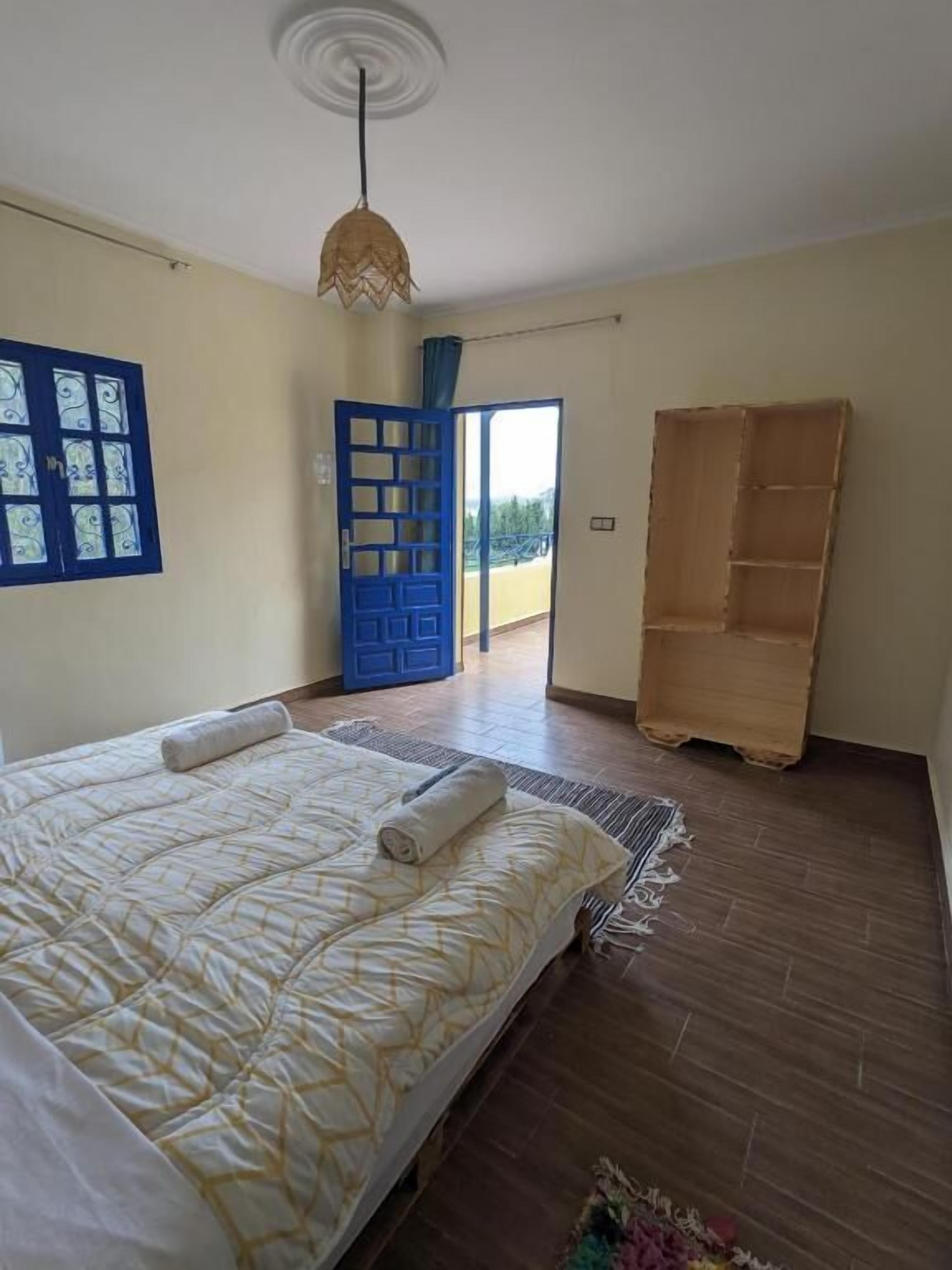 Un dormitorio con una cama, una puerta azul y un armario de madera.