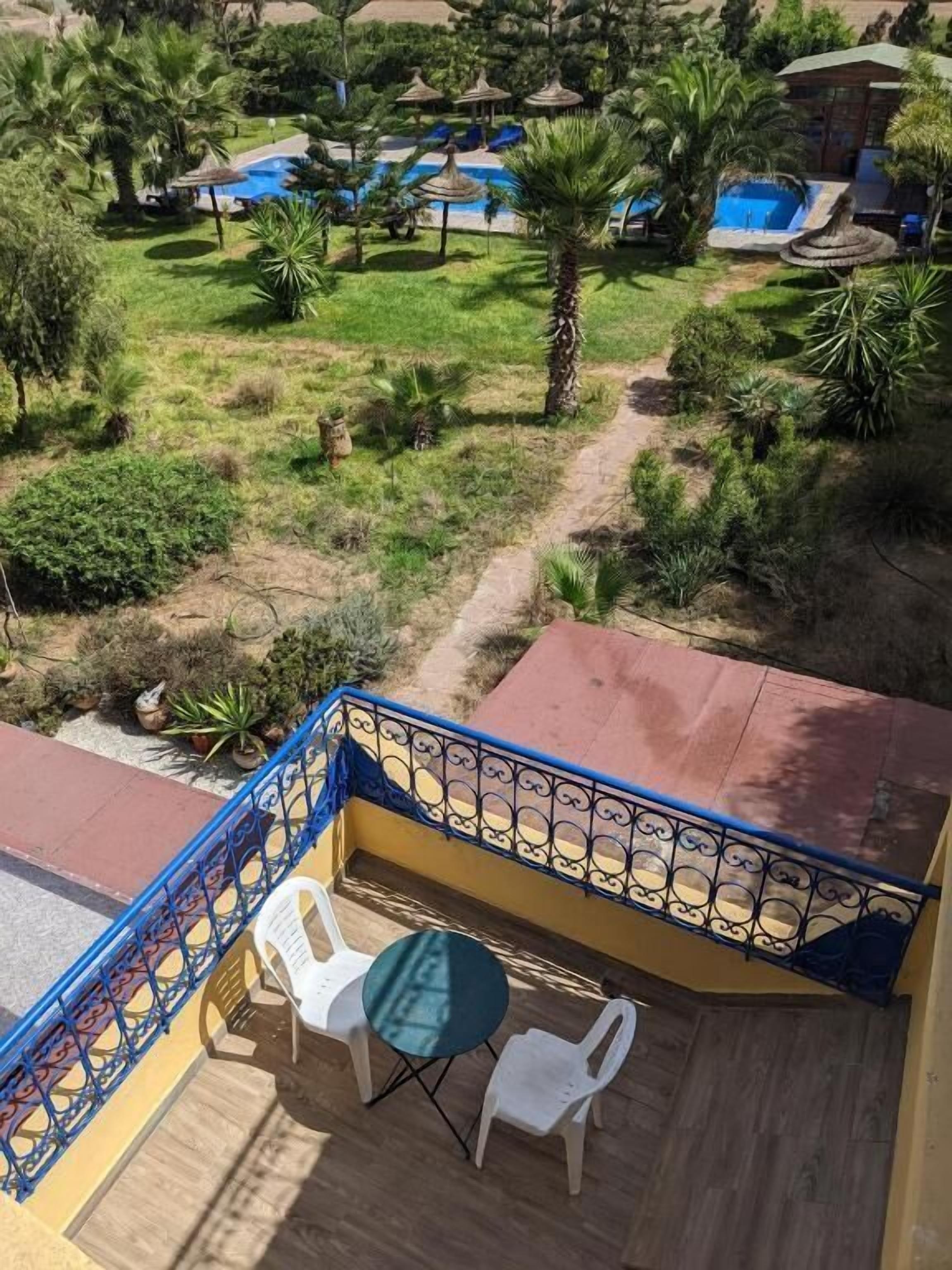 A balcony with a view of a pool and garden.
