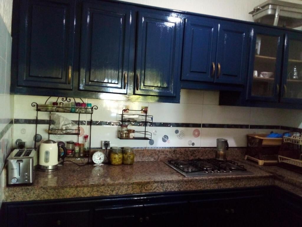 Una cocina con armarios azul oscuro, una estufa a gas, un tostador y un reloj en la pared.
