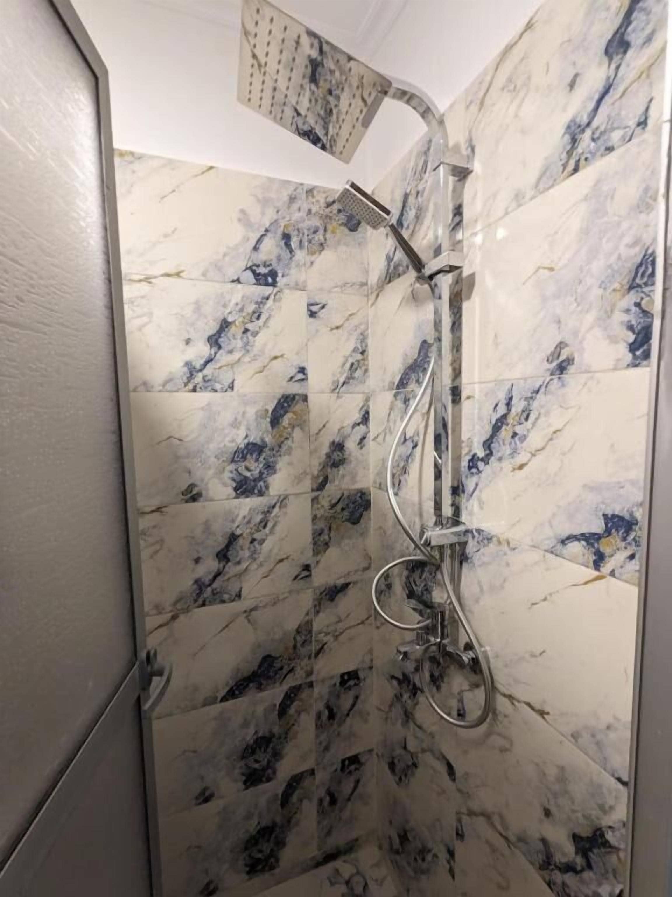 A shower with a curved showerhead and a handheld shower attachment.
