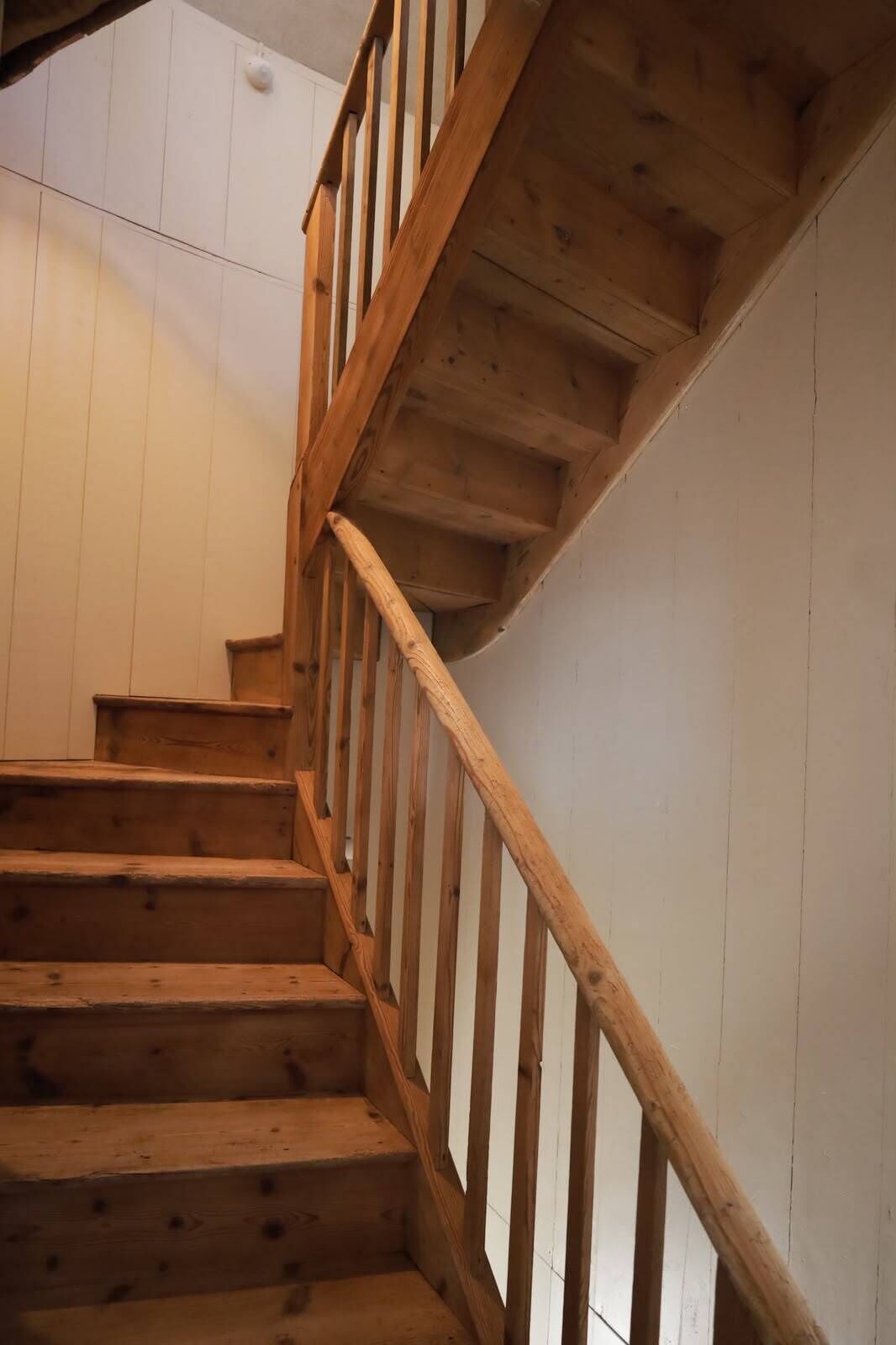A wooden staircase with a handrail, leading to an upper floor.