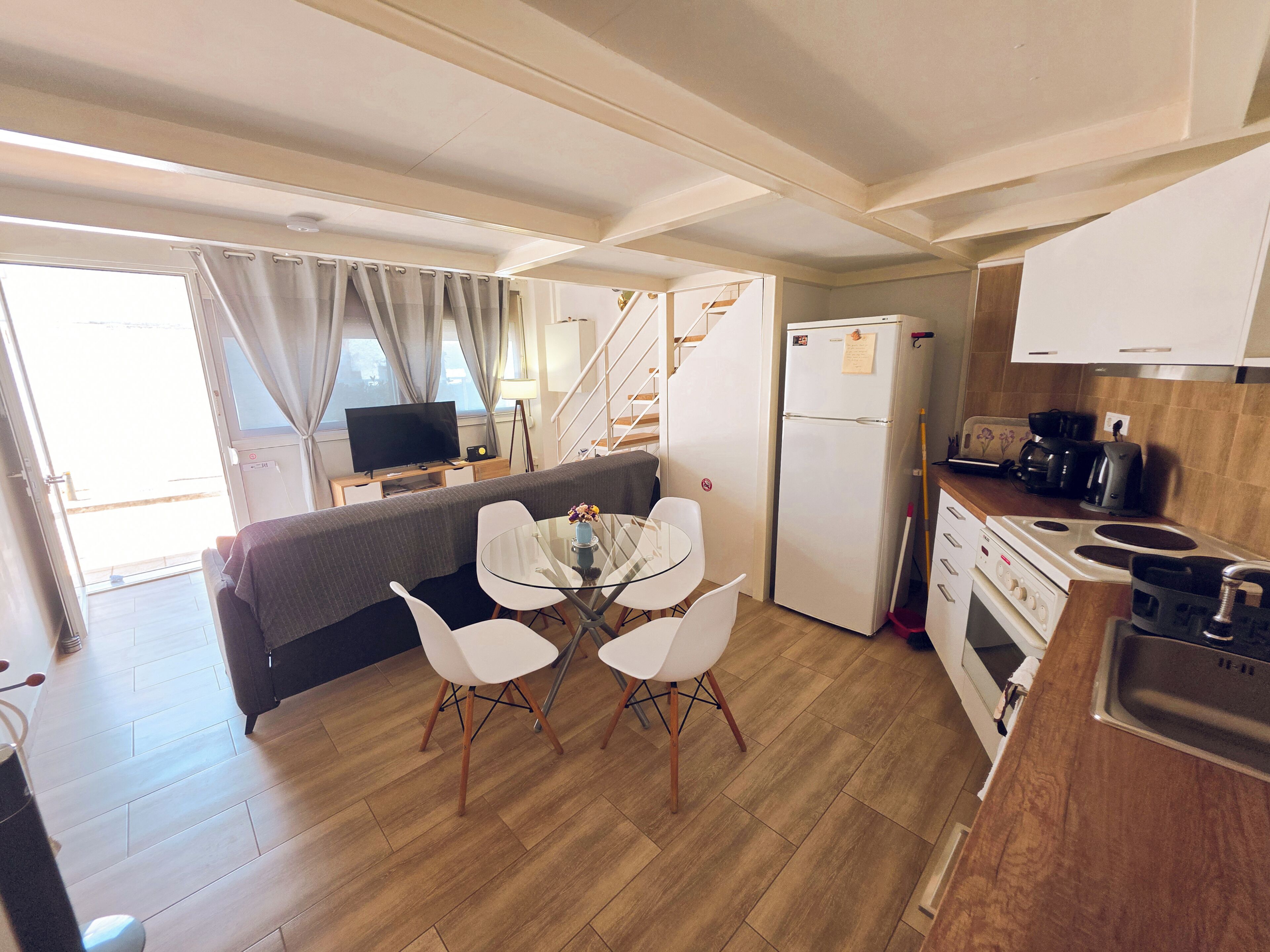 A compact kitchen with a dining area, a refrigerator, a stove, and a television.