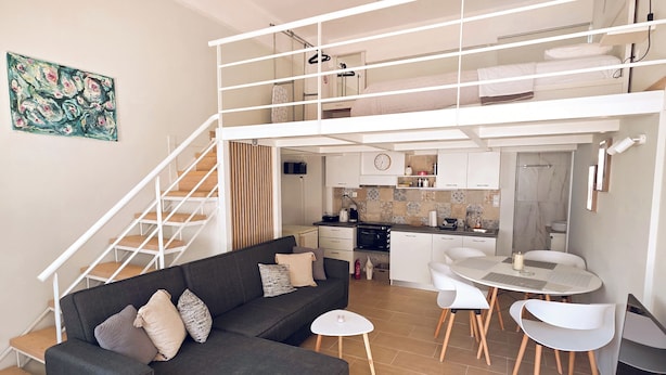 Um apartamento moderno com sala de estar, cozinha e um quarto no mezanino.