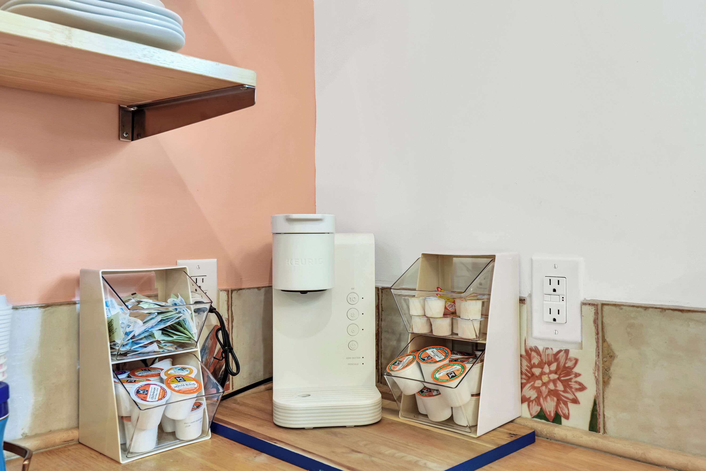A coffee machine, two coffee dispensers, and a shelf with coffee pods.