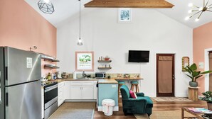 Moderni keittiö, jossa on jääkaappi, mikroaaltouuni ja puukehikoiset kaapit.