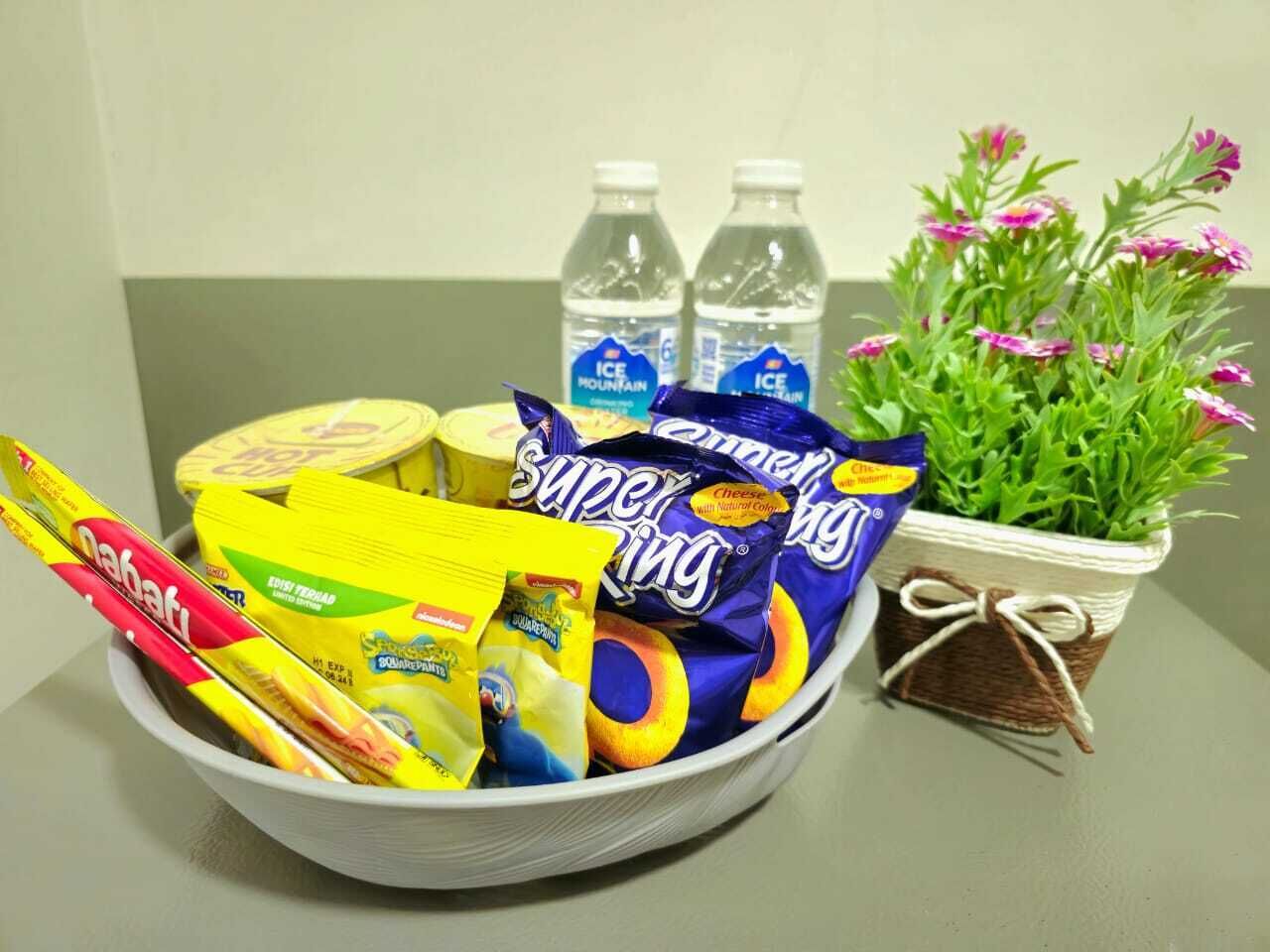A bowl filled with snacks, two water bottles, and a potted plant with flowers.