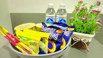 A bowl filled with snacks, two water bottles, and a potted plant with flowers.