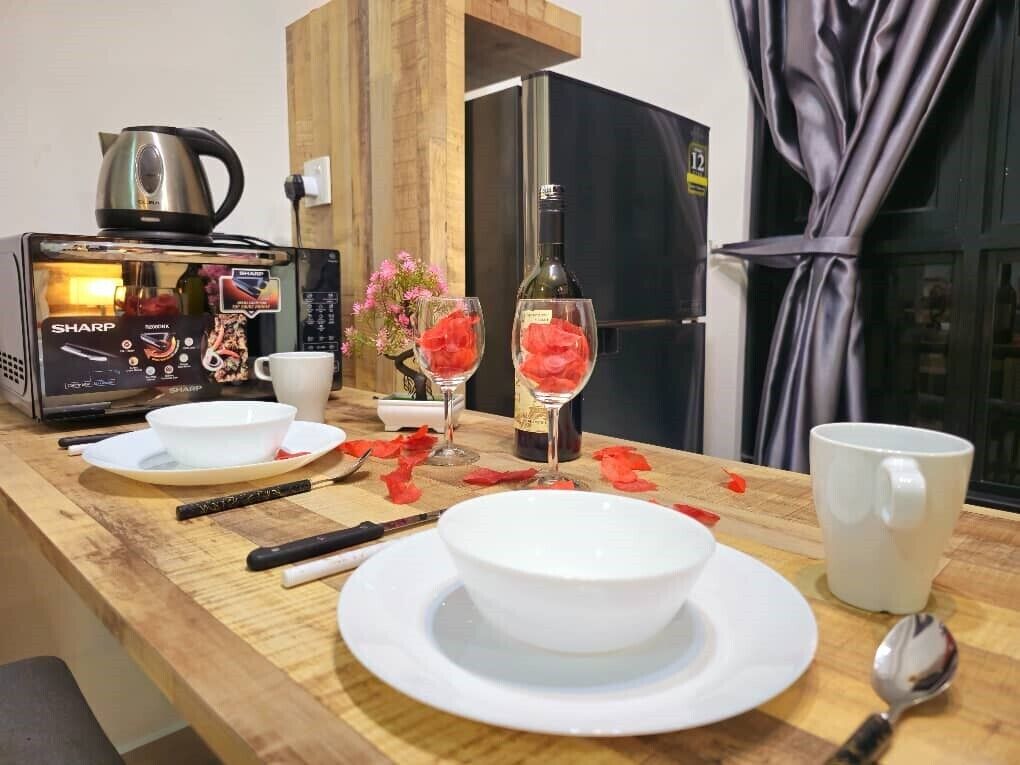 Una encimera de cocina con una cafetera, una botella, vasos y una cuchara.