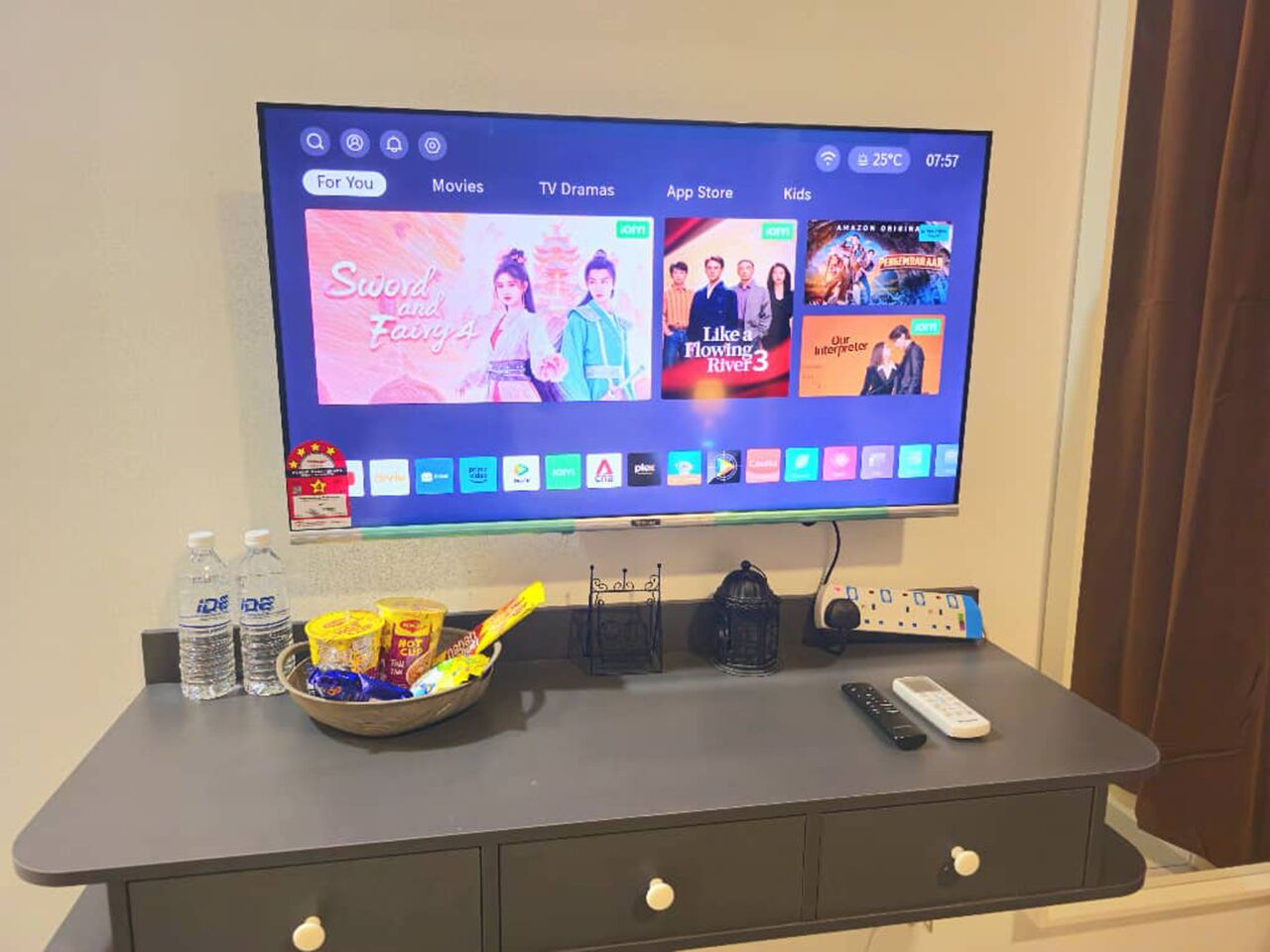 Un televisor de pantalla plana montado en una pared mostrando la interfaz de un servicio de streaming con opciones de películas.