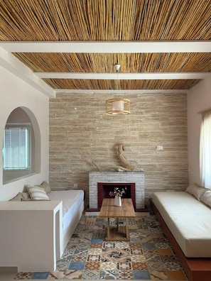 A living room with a fireplace, patterned floor tiles, and a bamboo ceiling.