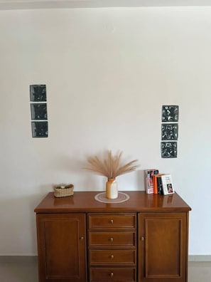 Un mueble de madera con cajones y un florero con plantas secas encima.