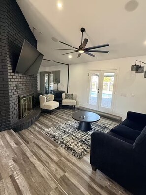 A modern living room with a fireplace, a ceiling fan, and a large window. - Private Pool Family Home Huge Backyard & Parking (Gilbert)