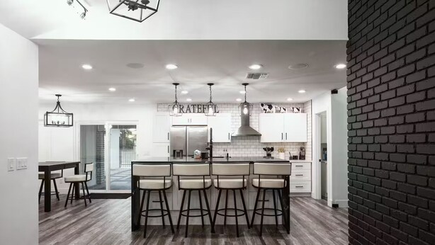 Una cocina moderna con una isla central, taburetes de bar e iluminación colgante.