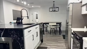 Una cocina moderna con una isla de mármol, electrodomésticos de acero inoxidable e iluminación colgante.