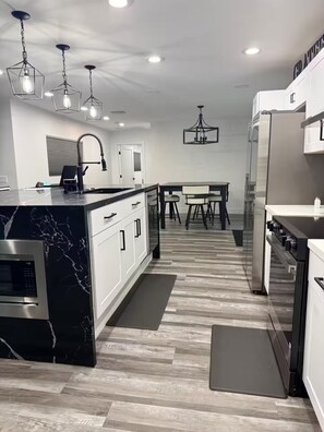 A modern kitchen with a marble island, stainless steel appliances, and pendant lighting. - Private Pool Family Home Huge Backyard & Parking (Gilbert)